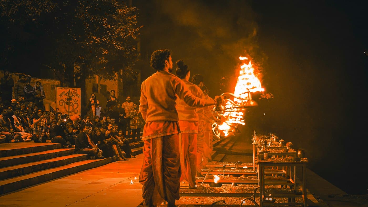 Priests performing evening Ganga Aarti with flaming brass lamps
