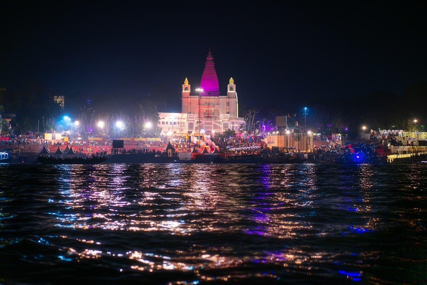 Illuminated riverside temple reflecting on the water at night